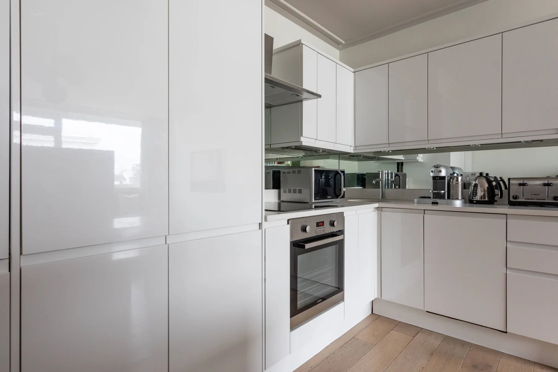 A modern kitchen with white cabinets, a built-in oven, and countertop appliances.