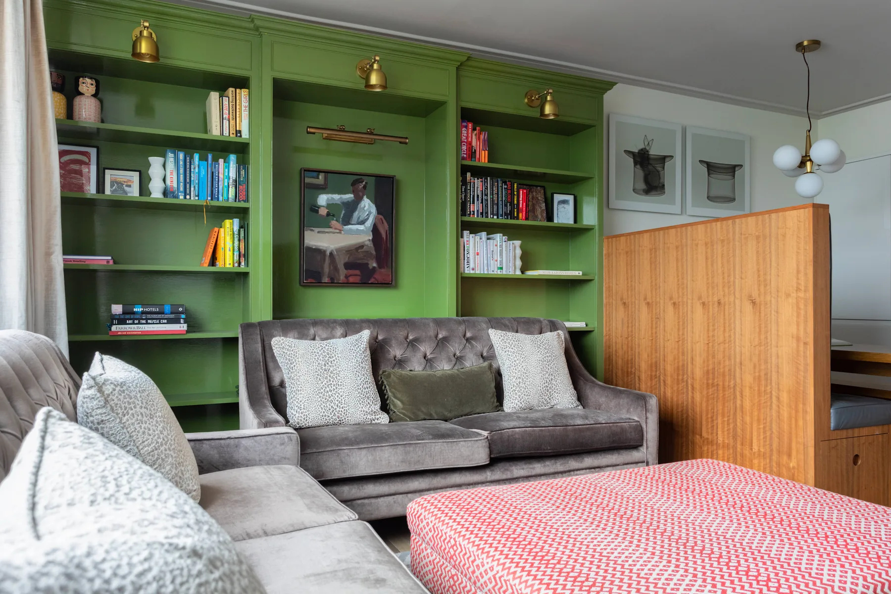 A living room with green built-in bookshelves and upholstered seating.