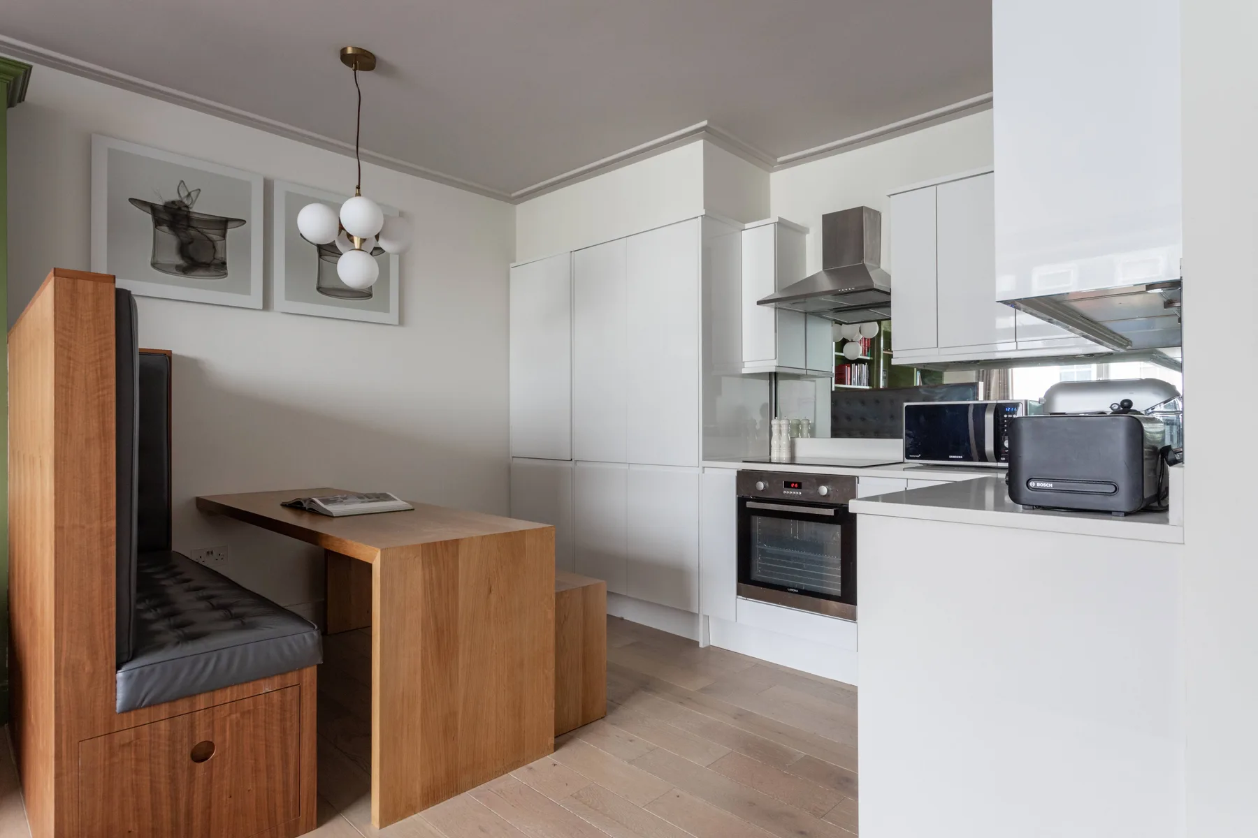 A compact kitchen and dining area with white cabinets and a wooden table.