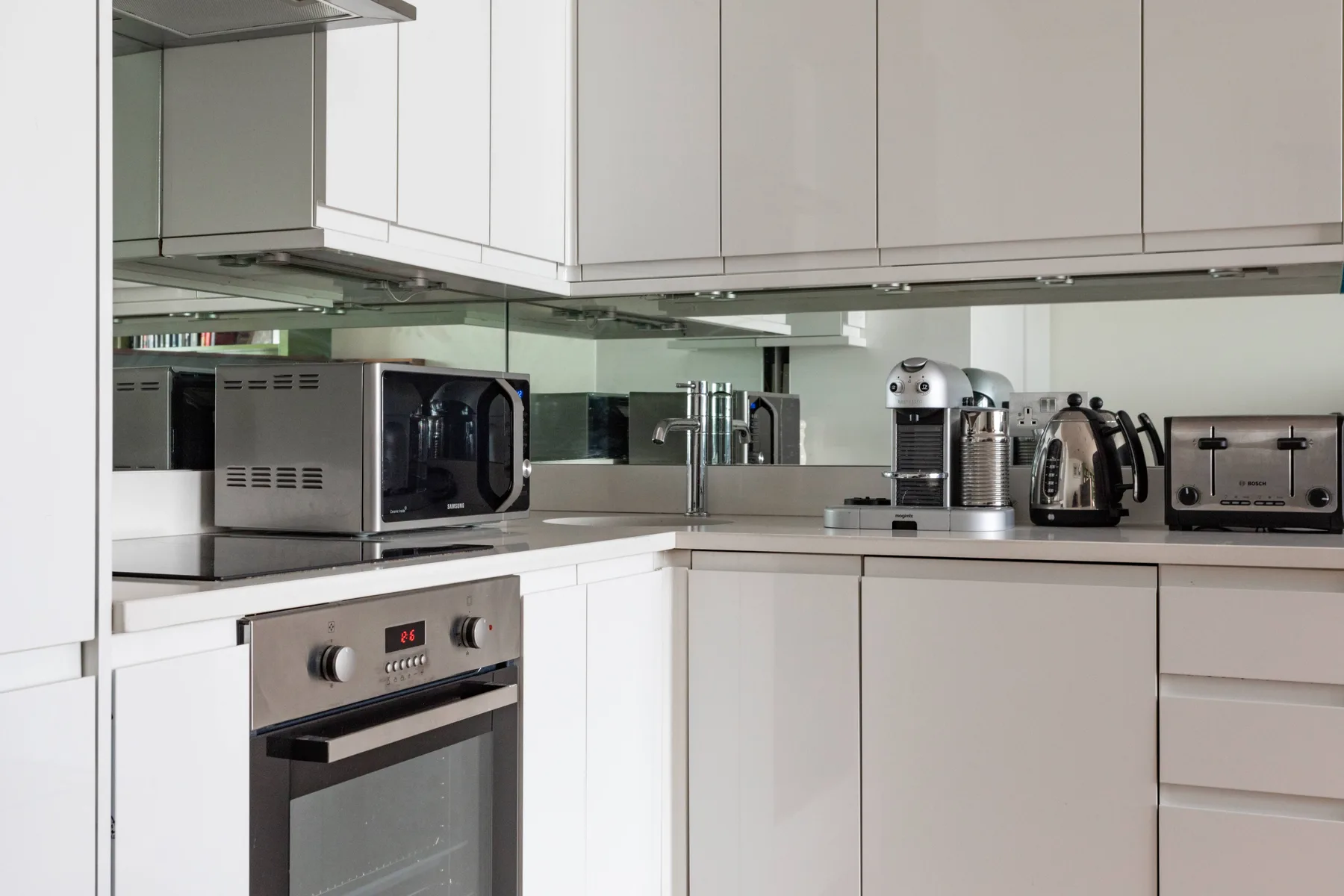 A modern kitchen with white cabinetry, a microwave, and countertop appliances.