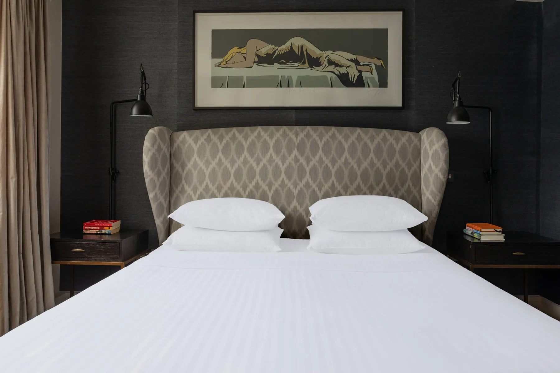 A bedroom with a neatly made bed and patterned upholstered headboard.