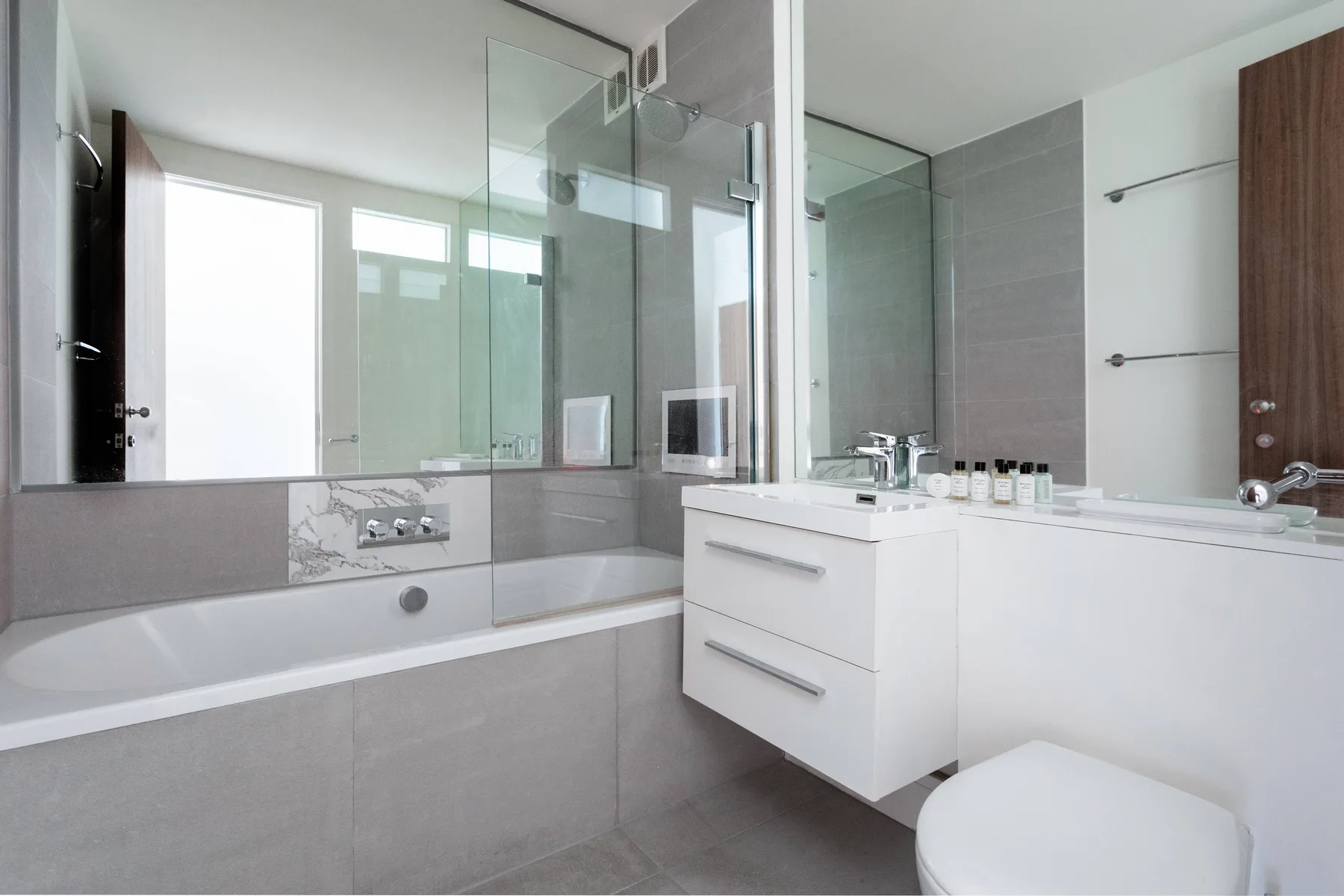 A modern bathroom with a bathtub, glass shower enclosure, and white vanity.