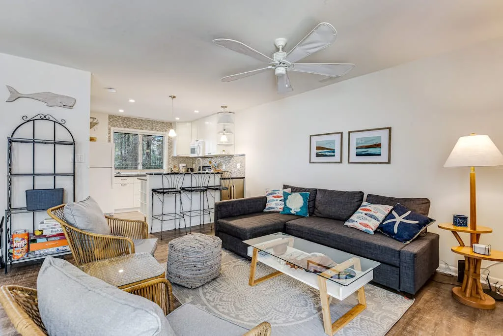 A bright living room with a sectional sofa and an open kitchen.