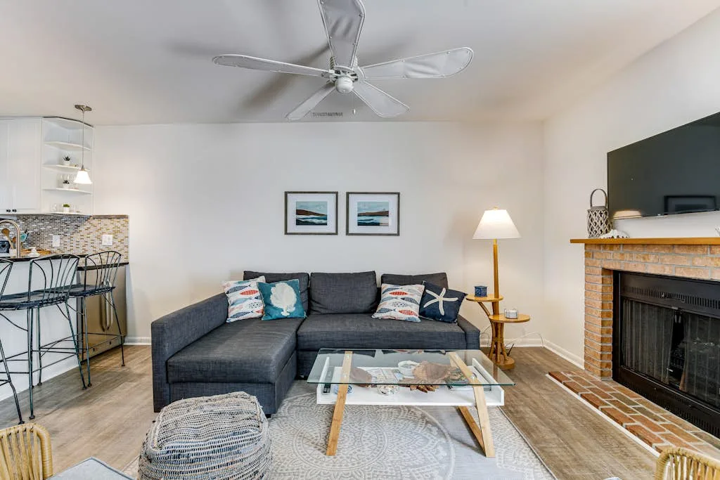 A living room with a sectional sofa, glass coffee table, and fireplace.