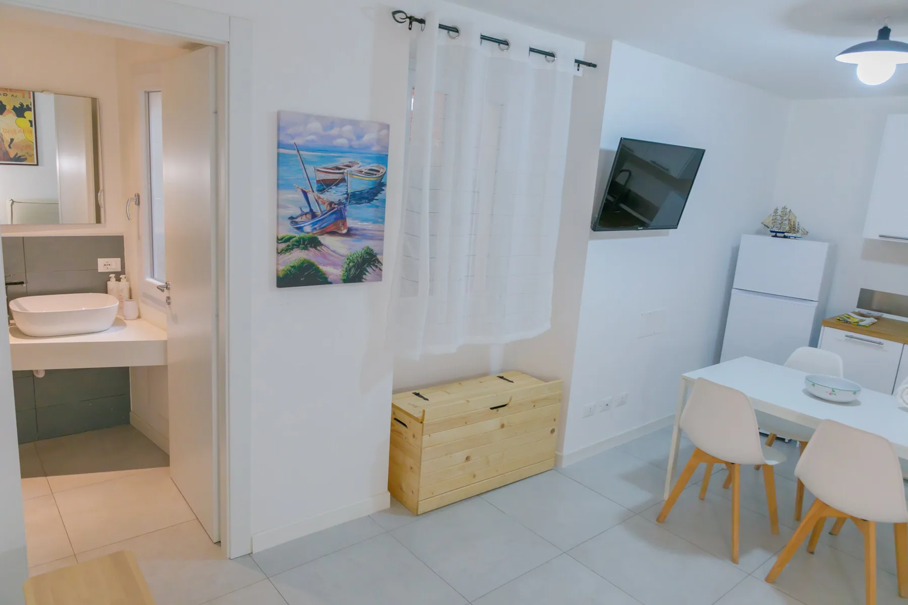A bright dining area with a table and chairs beside a small kitchenette.