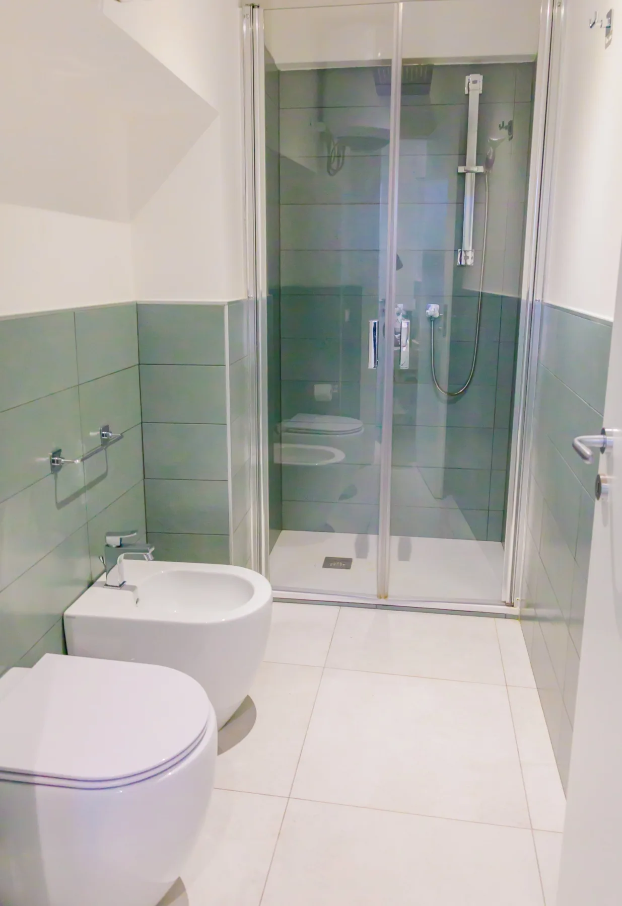 A tiled bathroom with a glass-enclosed shower and white toilet.