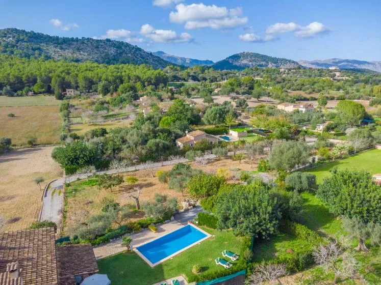 Vista aérea de un paisaje rural con una piscina y colinas boscosas.