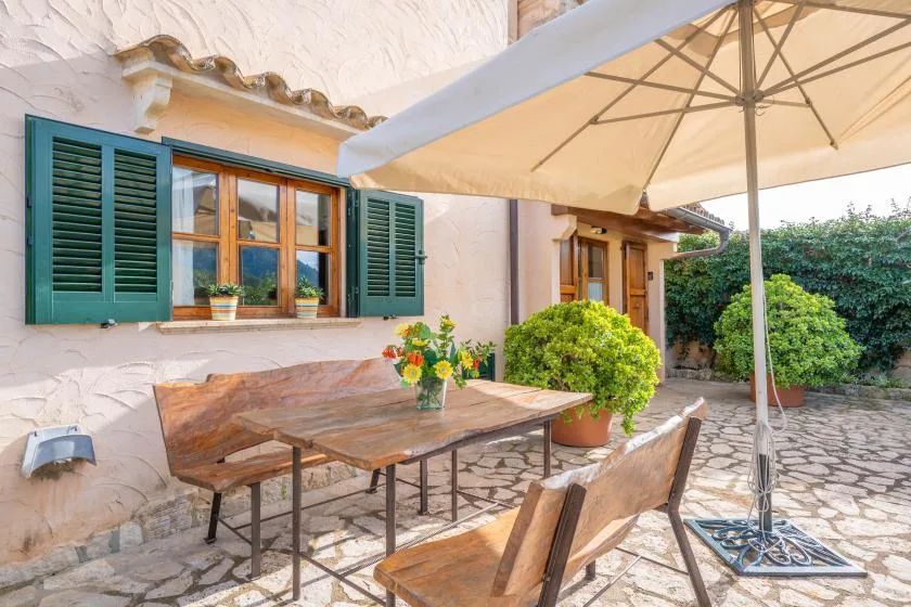 Un patio al aire libre con una mesa de madera bajo una gran sombrilla.