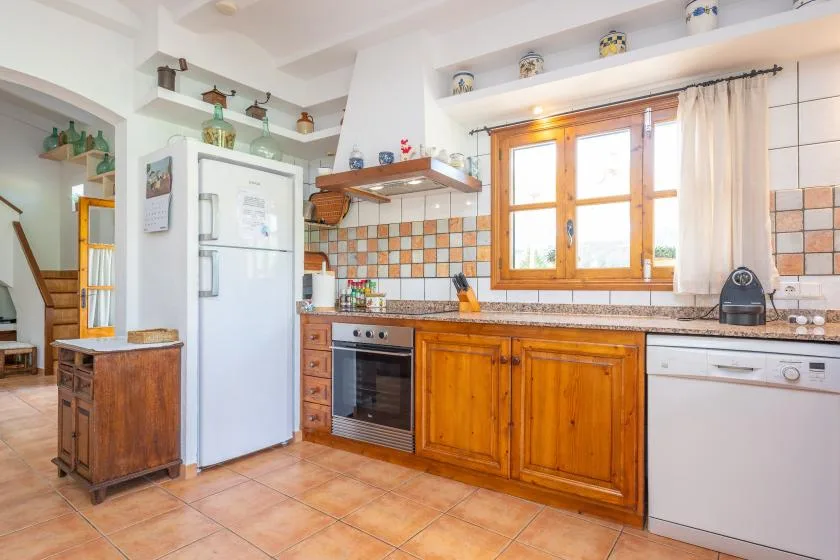 Una cocina con azulejos, armarios de madera y una ventana sobre la encimera.