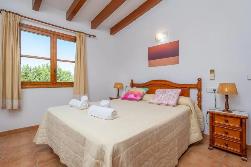 Un dormitorio con una cama grande, cabecero de madera y ventana con cortinas.