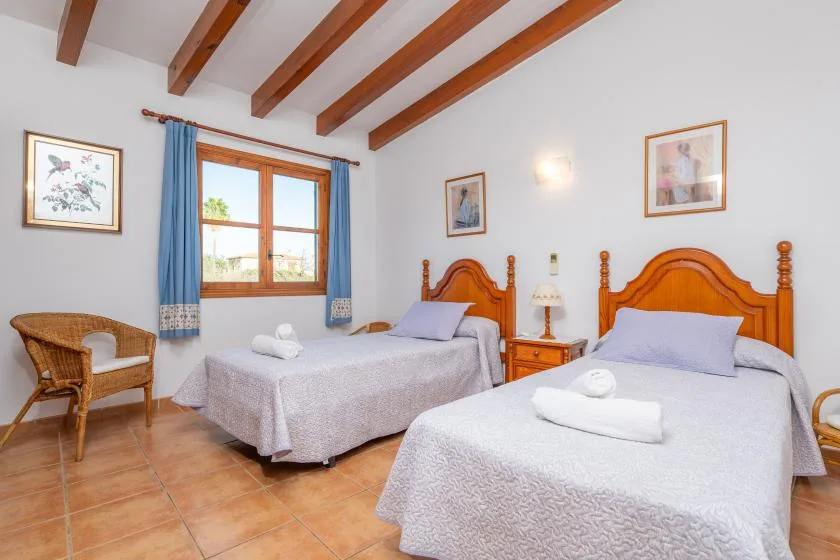 Un dormitorio con dos camas, una ventana y vigas de techo a la vista.