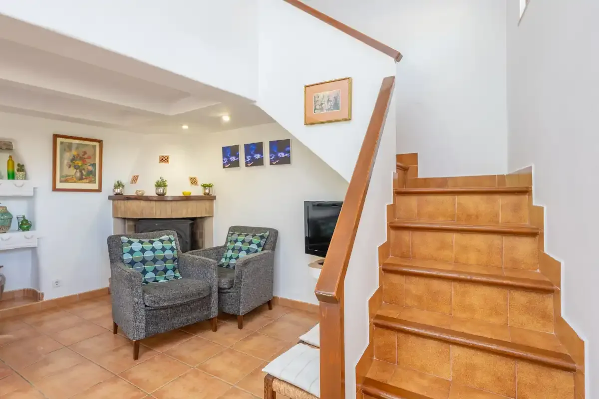 Una sala de estar con dos sillones junto a una escalera.