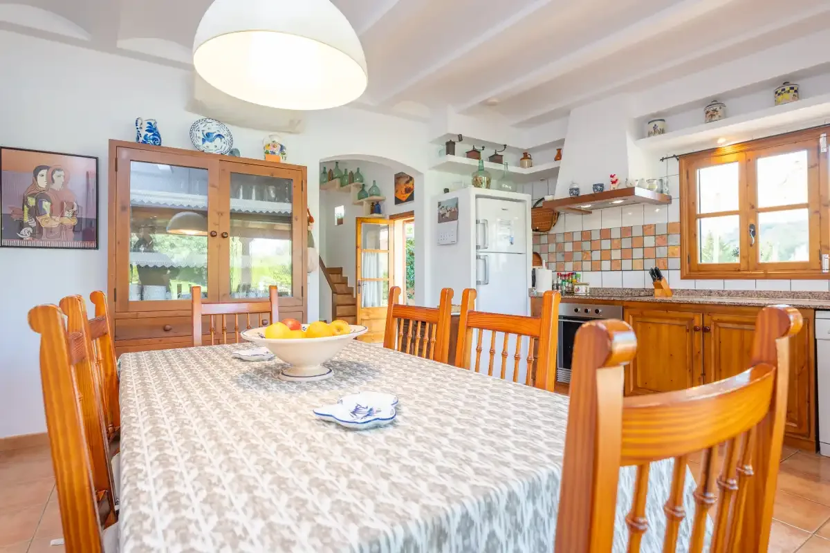 Comedor con una mesa larga y sillas junto a una cocina.