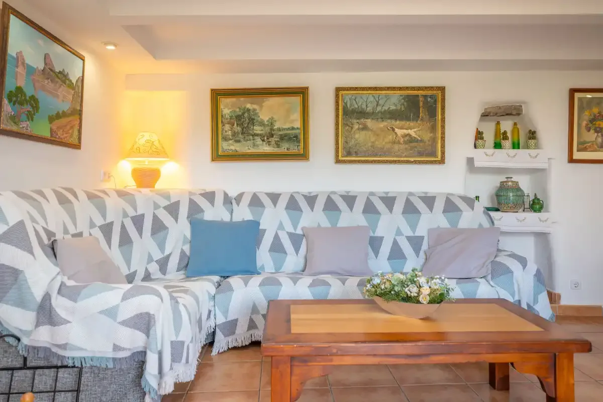 Una sala de estar con asientos estampados, cuadros enmarcados y una mesa de centro de madera.