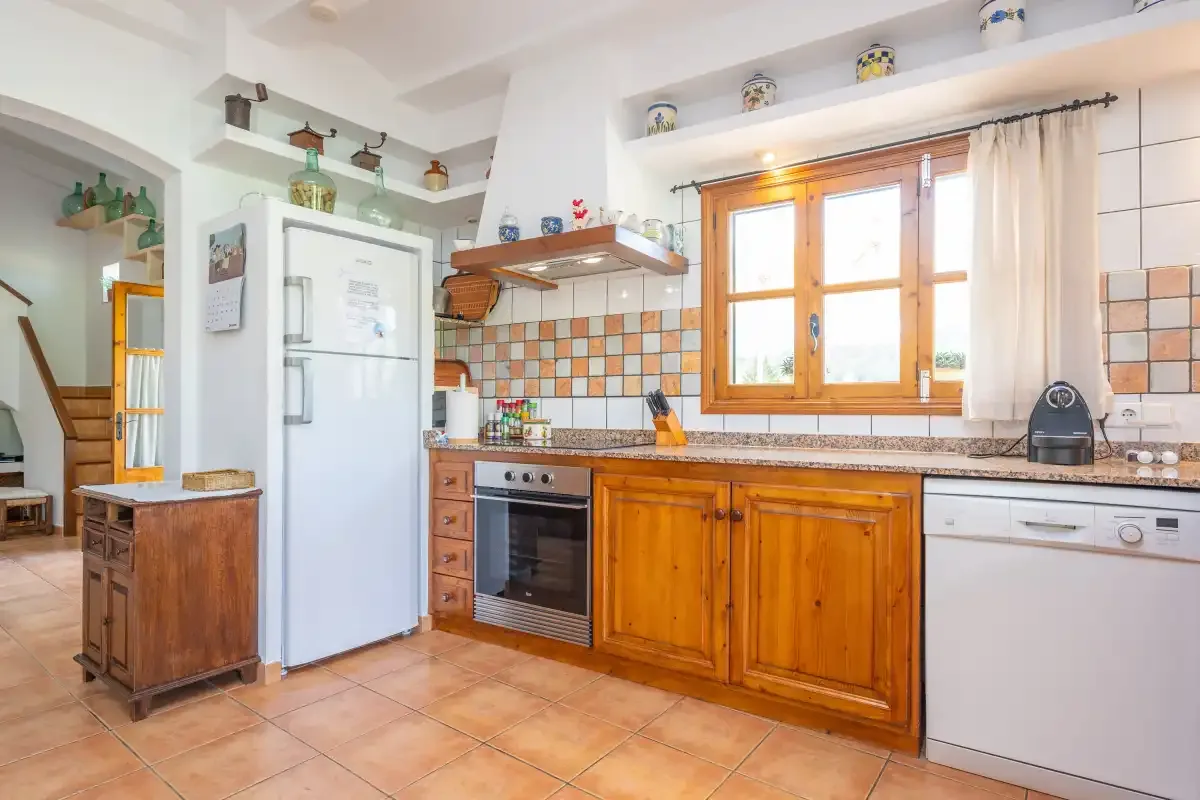 Una cocina luminosa con muebles de madera, una ventana y azulejos en la pared.