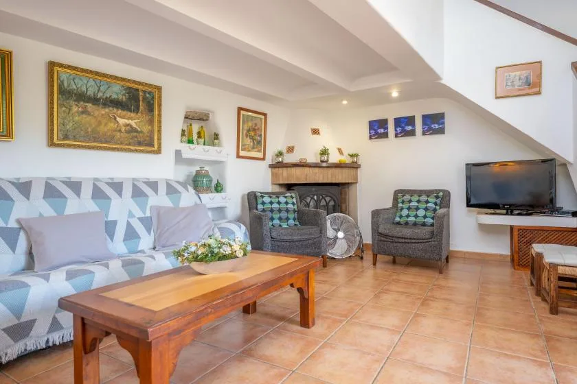 Una sala de estar con asientos estampados, una mesa de centro y un televisor.