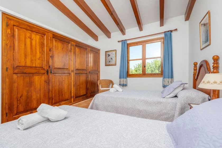 Un dormitorio con dos camas, armarios de madera y una ventana con cortinas azules.