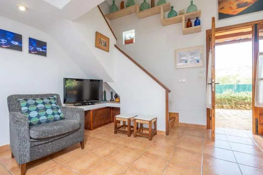 Una sala de estar con televisor, sillón y una puerta abierta.