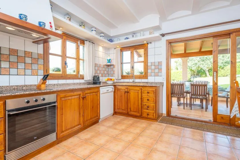 Una cocina con gabinetes de madera y una mesa de comedor visible a través de la puerta abierta.