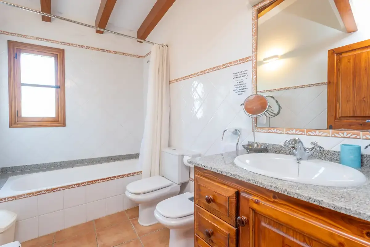 Un baño alicatado con lavabo, inodoro y mueble de madera.