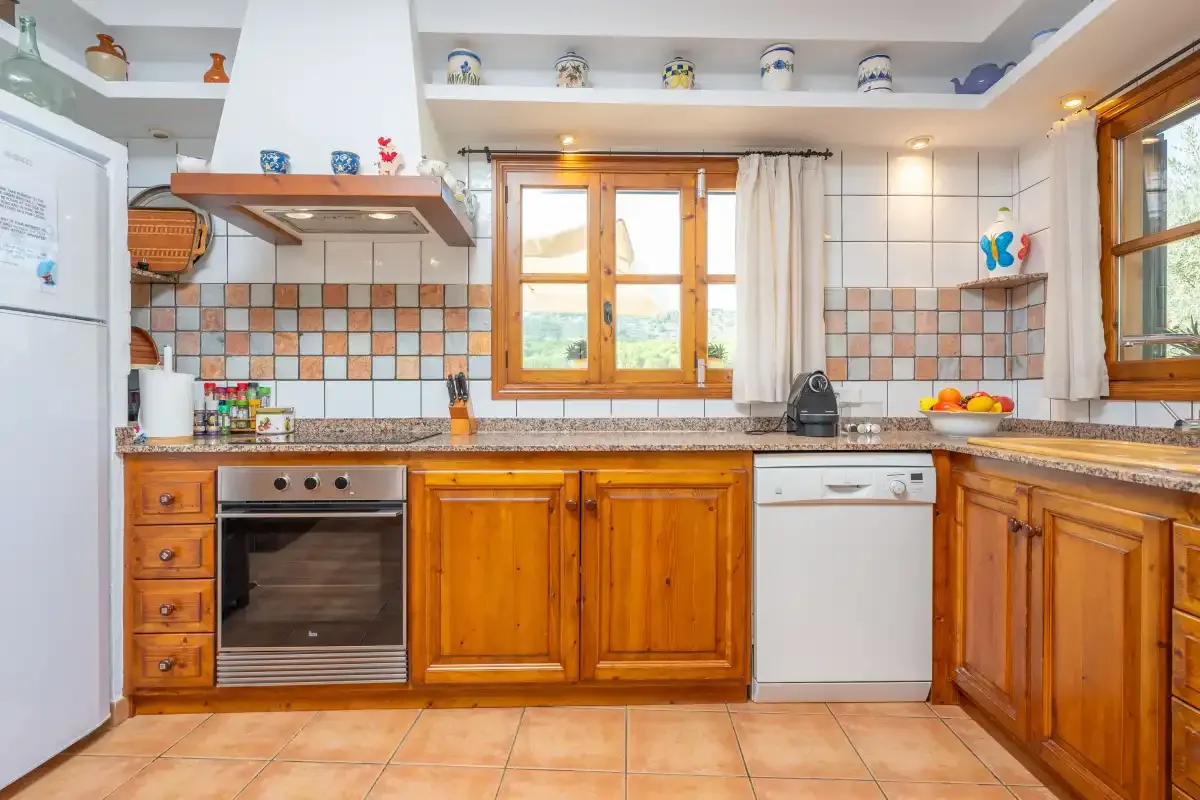 Una cocina alicatada con armarios de madera, un horno empotrado y una ventana.