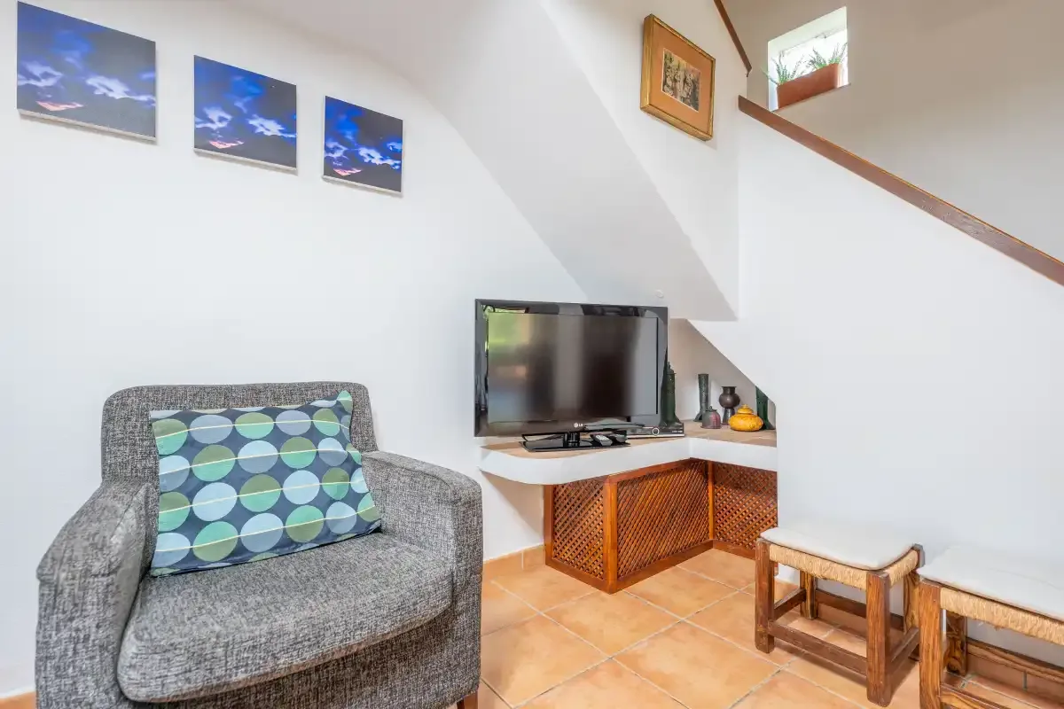 Una sala de estar con televisor, asientos y una pequeña mesa de madera.