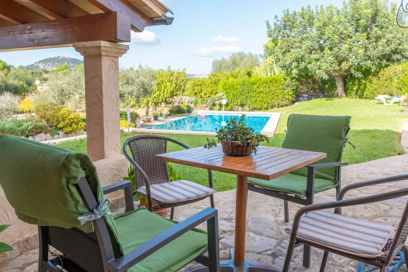 Una zona de estar en el patio da a una piscina y un jardín ajardinado.