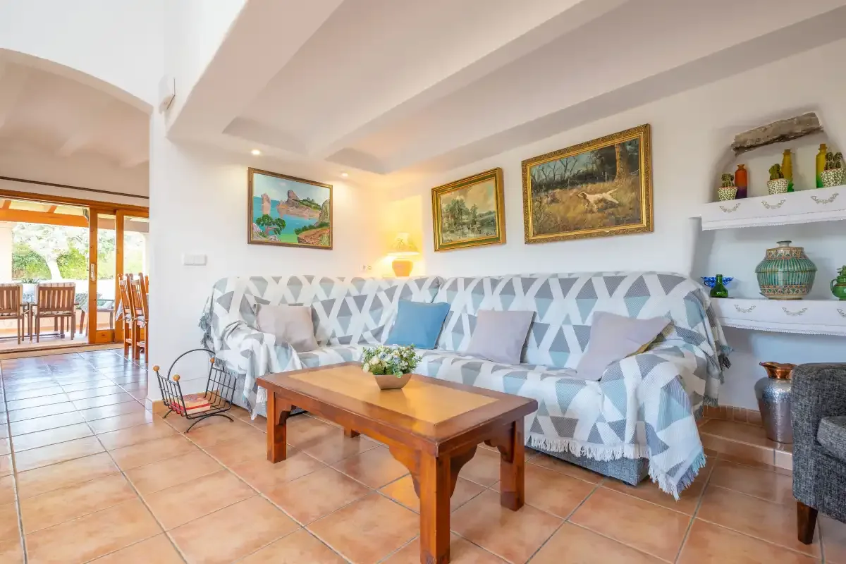 Una sala de estar con asientos estampados, una mesa de centro de madera y cuadros enmarcados.