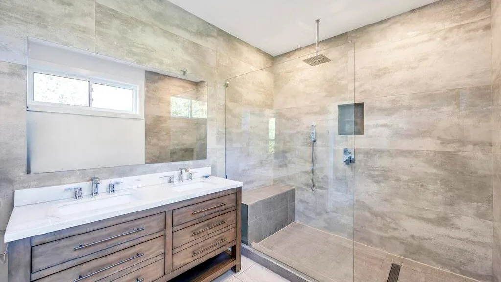 Un baño con un lavabo amplio y una ducha con mampara de vidrio.