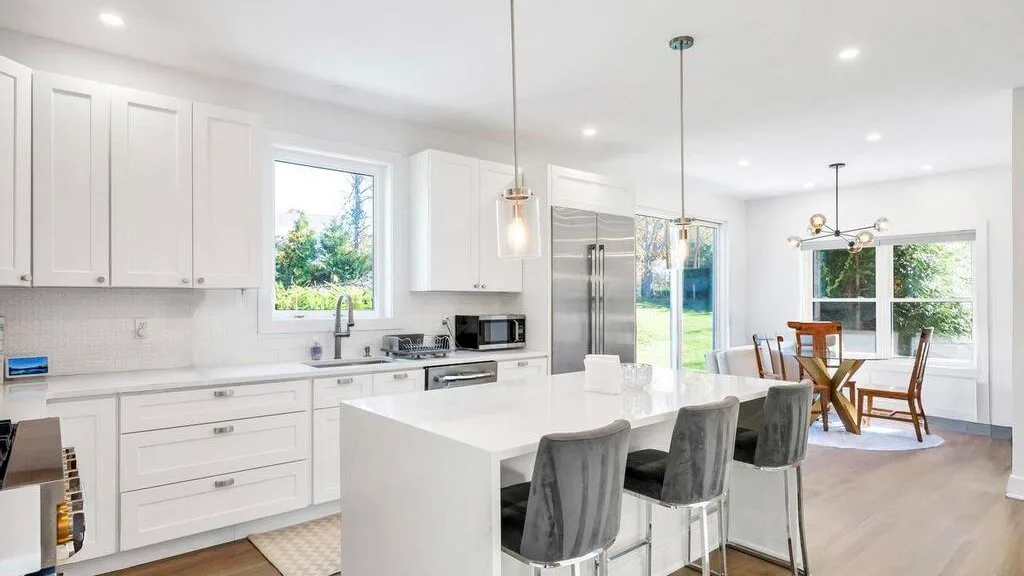 Una cocina y comedor luminosos con gabinetes blancos e isla central.