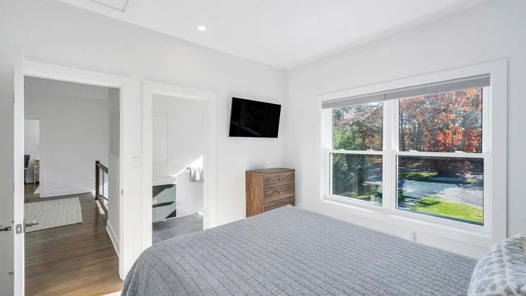 Un dormitorio luminoso con una cama bajo una ventana grande.
