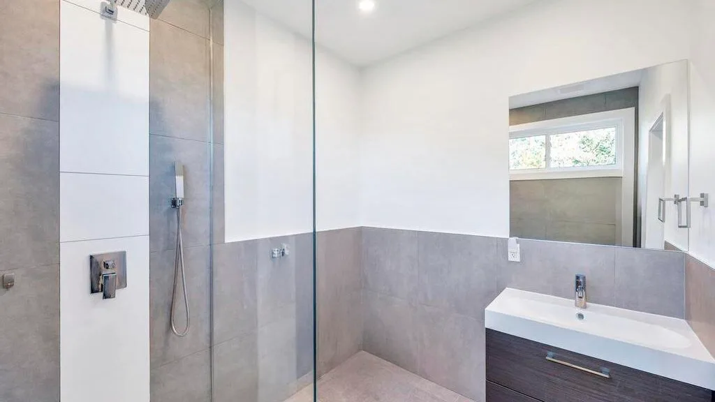 Un baño moderno con una ducha de vidrio y un tocador.