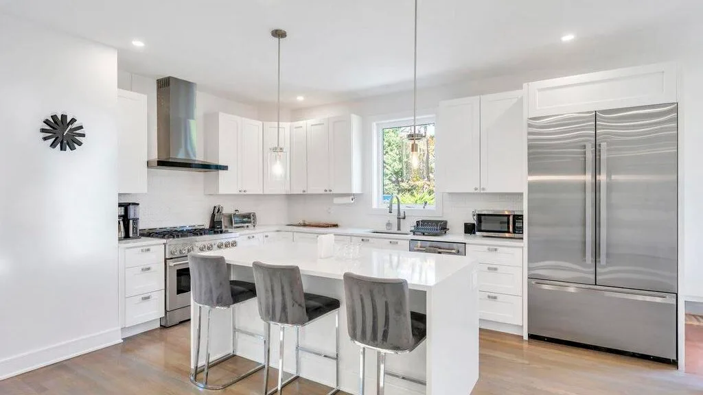 Una cocina moderna y luminosa con una isla central y electrodomésticos de acero inoxidable.