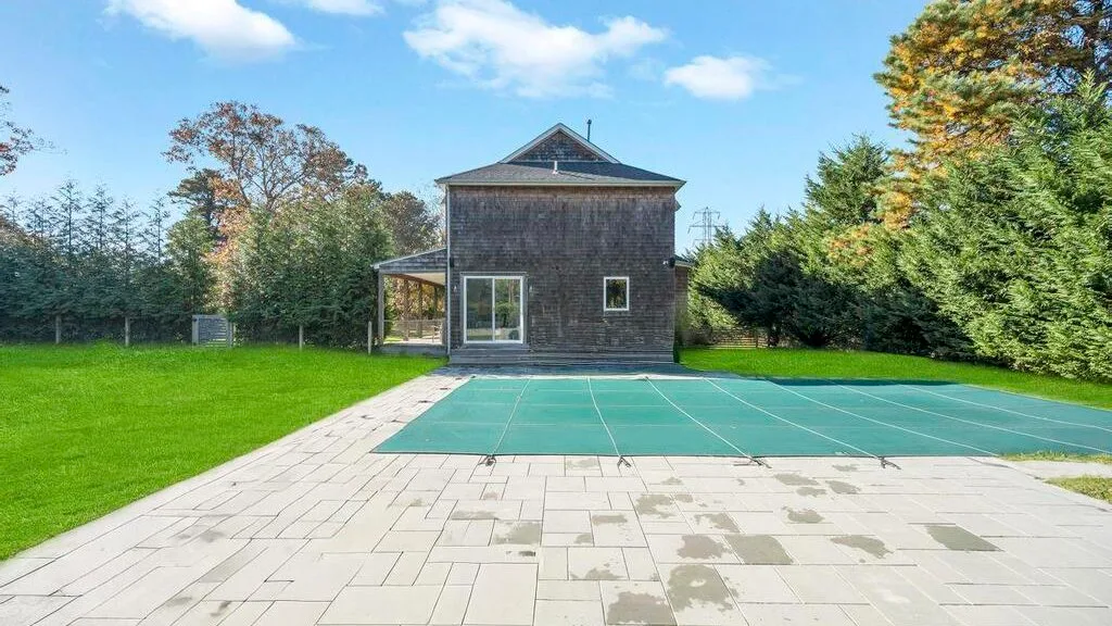 Un patio exterior junto a un edificio pequeño, con una pista verde y árboles alrededor.