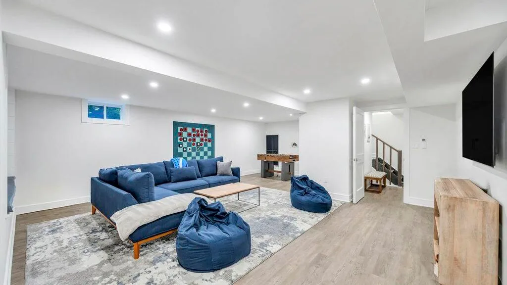 Una sala luminosa con asientos azules, una alfombra y un televisor.