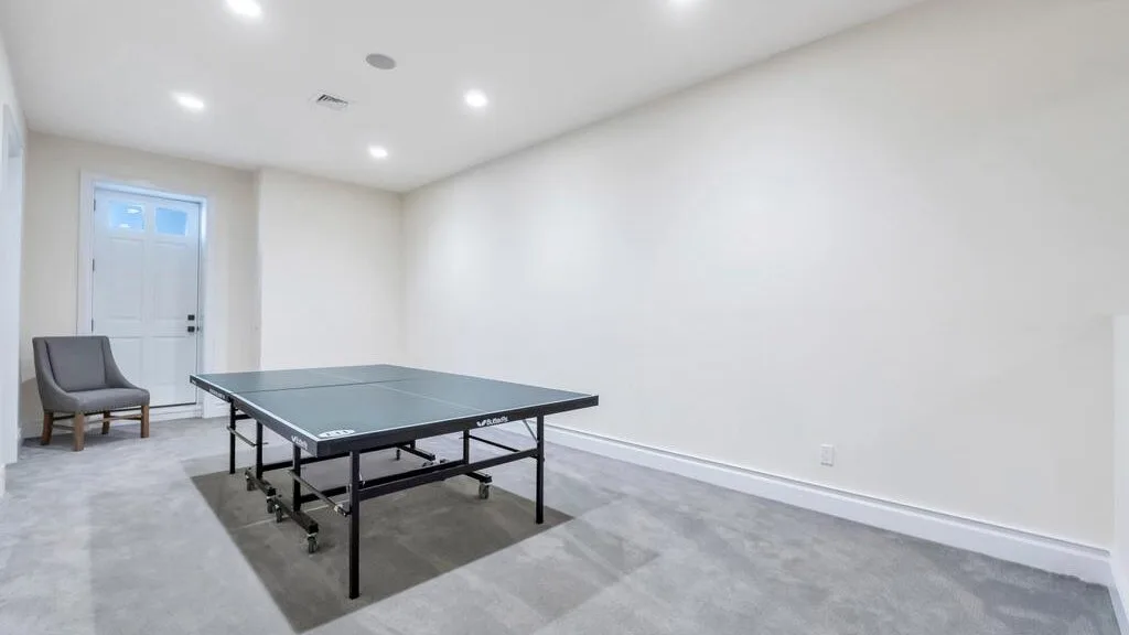 A basement recreation room with a ping-pong table and a chair.