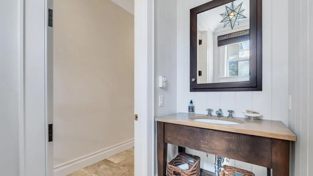 A bathroom vanity with a mirror and a doorway to an adjoining hall.