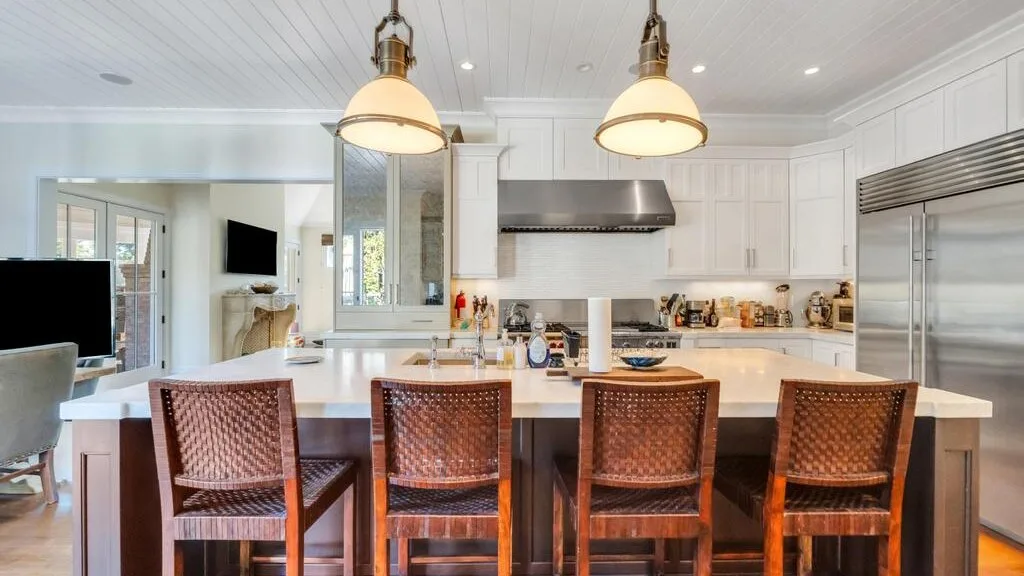 A bright kitchen with a large island and woven seating.