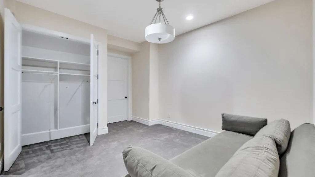 An empty bedroom with an open closet and gray carpet.