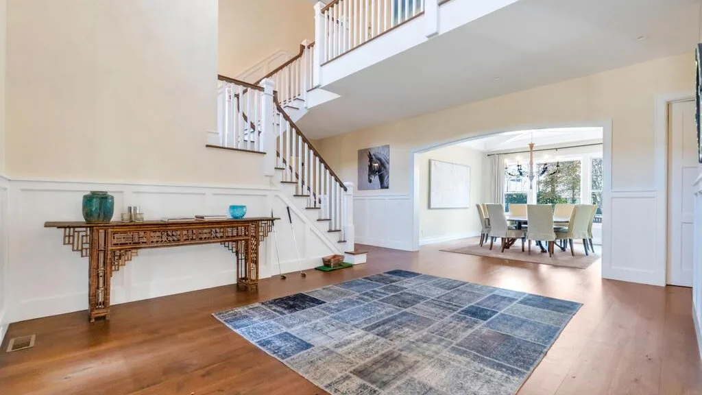 A bright foyer features a staircase beside an open dining area.