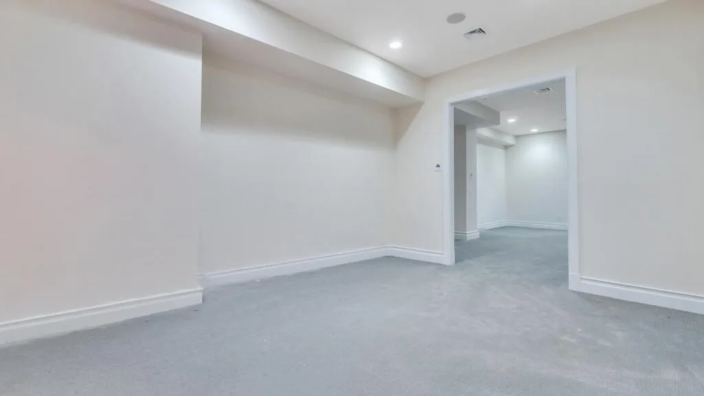 A bright, empty interior room with gray flooring and an open doorway.