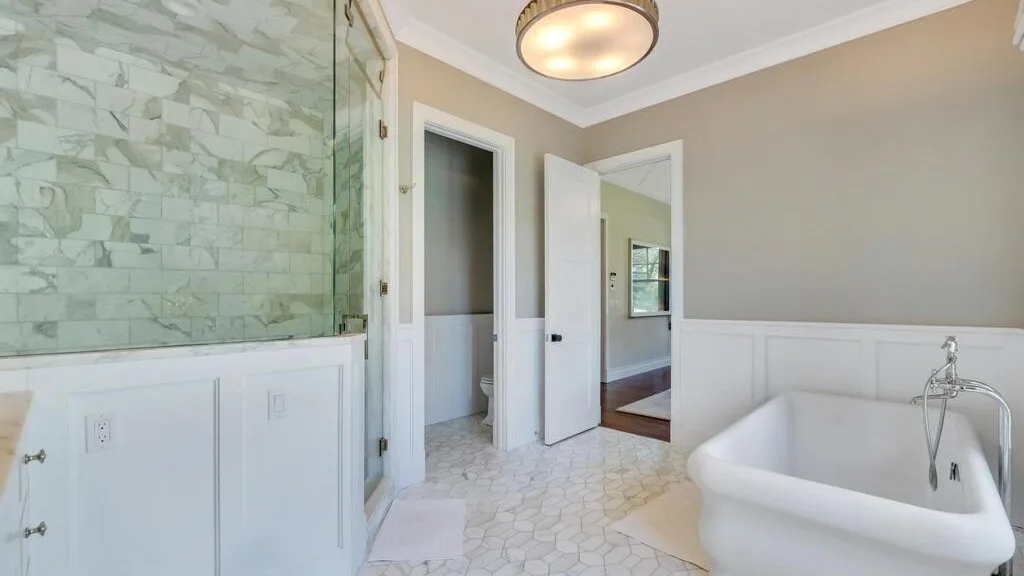 A bathroom with a freestanding bathtub and a tiled shower area.