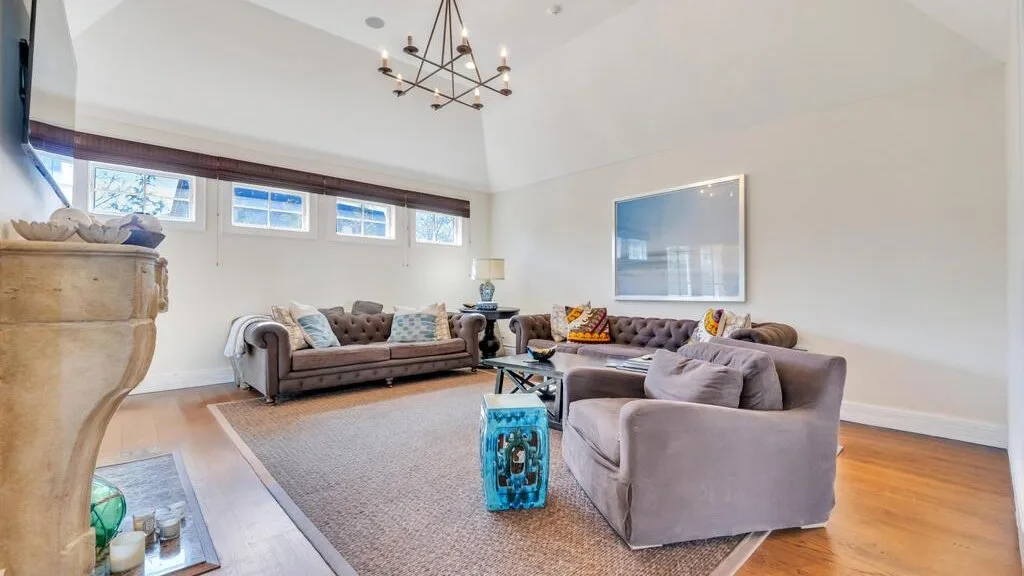 A bright living room with seating arranged around a rug and coffee table.