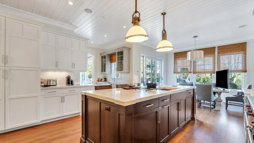 A bright kitchen with a large central island and pendant lights.