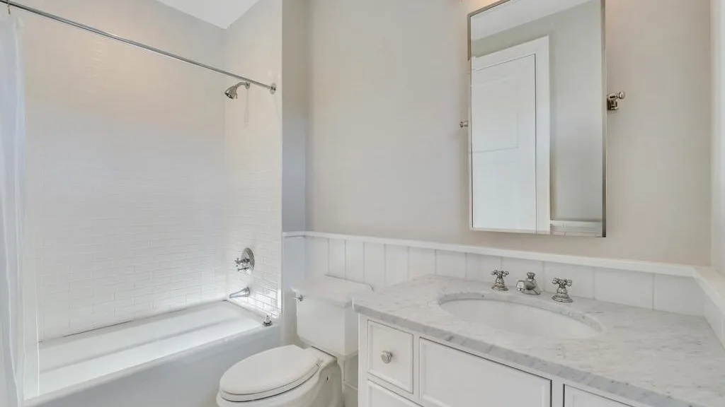 A bathroom with a bathtub and a sink vanity beneath a wall mirror.