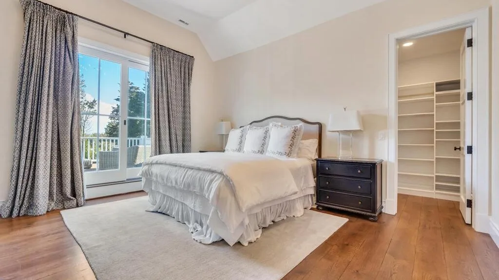 A bedroom with a bed beside a window and an open closet.