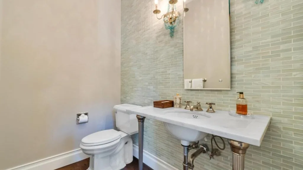A bathroom with a long sink counter, mirror, and toilet.