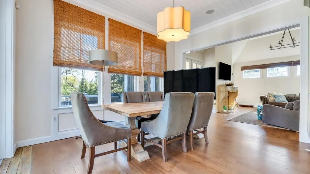 A bright dining area with a wooden table and large windows.