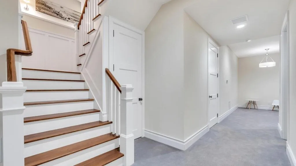 A bright interior hallway with a staircase and white walls.