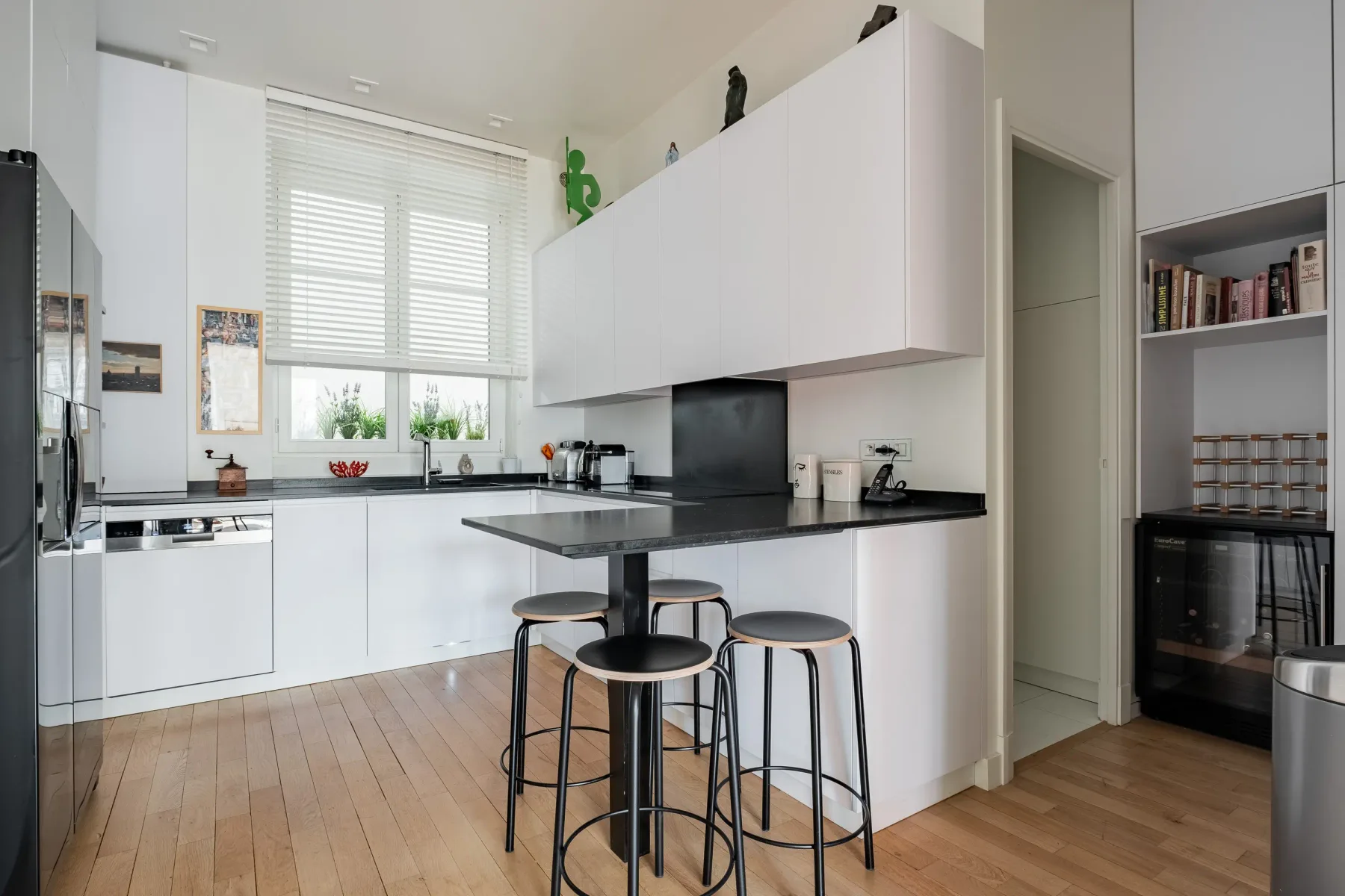 A bright kitchen with white cabinets, a dark countertop, and bar seating.